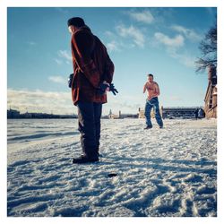People on snow covered land against sky