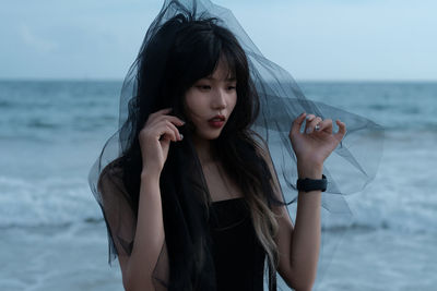 Portrait of young woman standing at beach