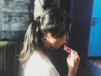 Side view of young woman eating sweet food while standing outdoors