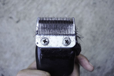 Cropped hand of man holding electric razor with hairs