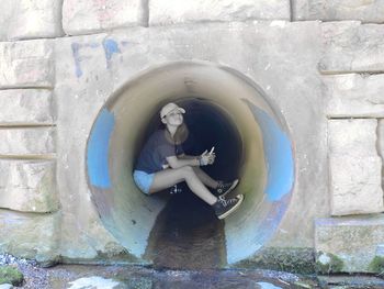 Woman sitting by wall