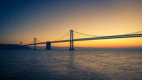 Bay bridge against clear sky at sunrise