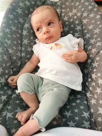 Portrait of cute baby boy sitting on sofa at home