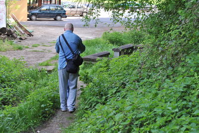 Rear view of man walking by plants
