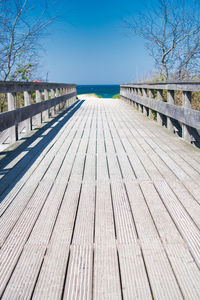 Surface level of boardwalk on footbridge against clear sky