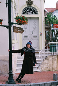 Portrait of woman standing against building