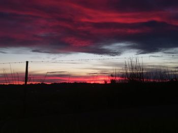 Silhouette landscape against dramatic sky during sunset