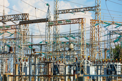 A network of wires with metal masts and high voltage dielectric insulators against a blue cloudy sky