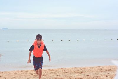 Boy running at beach against sky