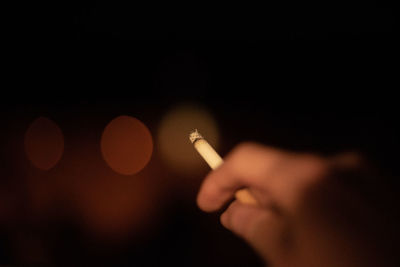 Cropped hand smoking cigarette at night