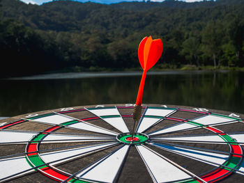 Close-up of red umbrella on lake against trees