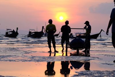 Rear view of silhouette people walking on beach during sunset