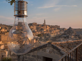 Close-up of illuminated cityscape against sky during sunset. matera, italy