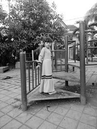 Rear view of woman standing on footpath by street against building