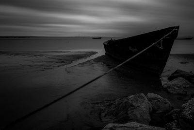 Boat moored on beach against sky