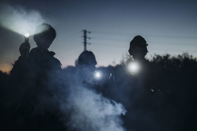 Group of three children camping and playing with torch lantern in the dark