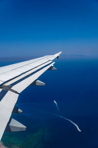 Airplane flying over sea against blue sky