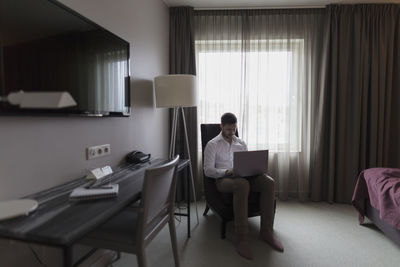 Man using laptop in bedroom