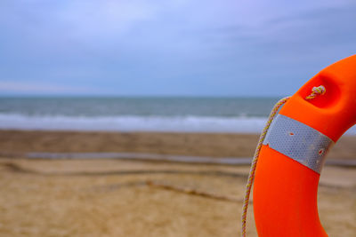 Red wooden post on beach against sky