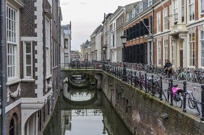 People on bridge over canal amidst buildings in city