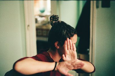 Woman covering face with hands at home