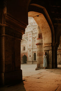 Full body back view of anonymous female tourist standing under arched passage of muhammad shah sayyid tomb at lodhi garden in new delhi