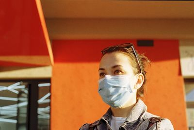 Close-up of woman wearing mask standing against building