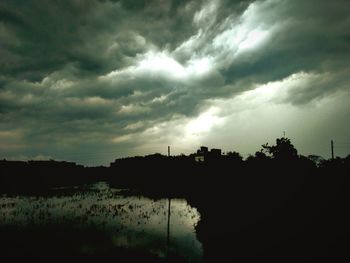 Silhouette of trees against cloudy sky