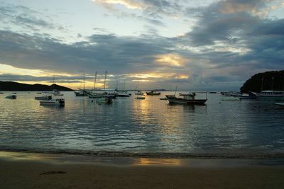 Sailboats sailing in sea against sky during sunset