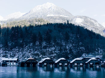 Houseboats in river against snowcapped mountains