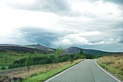 Scenic view of road by mountains against sky