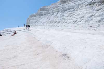 Tourist walking on scala dei turchi against clear sky