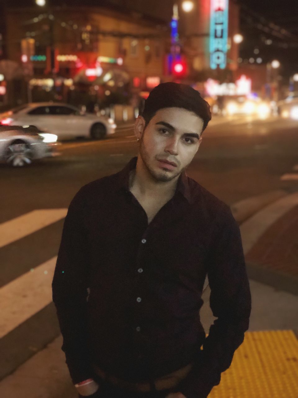 city, night, one person, young adult, illuminated, street, looking at camera, young men, architecture, portrait, waist up, car, building exterior, front view, standing, focus on foreground, real people, motor vehicle, built structure