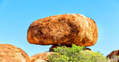 Low angle view of rock against clear blue sky