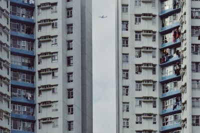 Low angle view of airplane amidst residential buildings