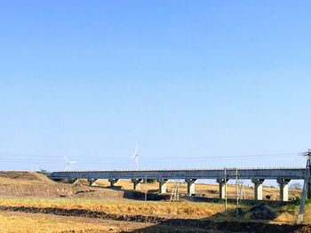 Bridge over field against clear blue sky
