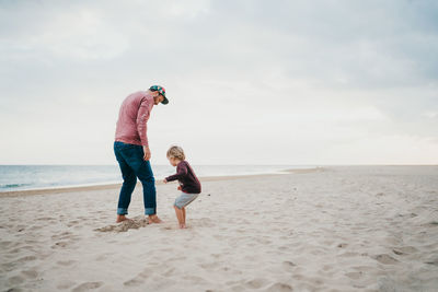 Father and child son playing a the beach on a cloudy day