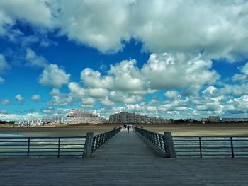 Bridge over calm sea against sky in city