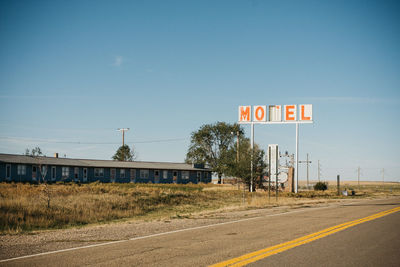 Information sign by road against sky