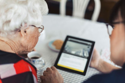 High angle view of caretaker and senior woman using digital tablet at home