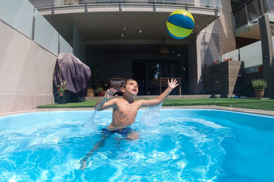 Athletic boy playing with a ball on a swimming pool