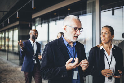 Female and male coworkers walking while talking in corridor at workplace