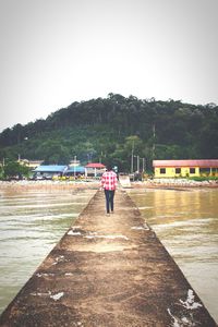 Full length of woman standing on railing by sea