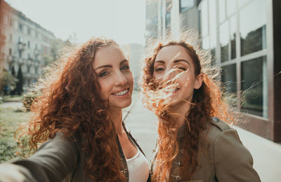 Portrait of smiling young women doing selfie outdoors