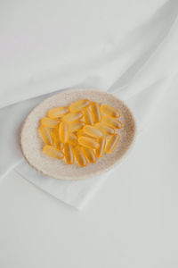 Large yellow omega jelly pills and vitamin on an eco-friendly natural stone plate on white