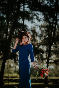 Young woman wearing hat standing against plants