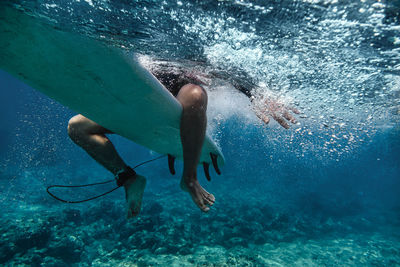 Male surfer sitting on surfboard while surfing in sea at maldives