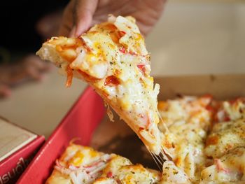 Close-up of hand holding pizza