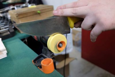 Cropped hand of man sharpening knife in workshop