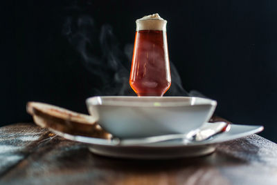 Close-up of soup with toasted bread on wooden table against black background